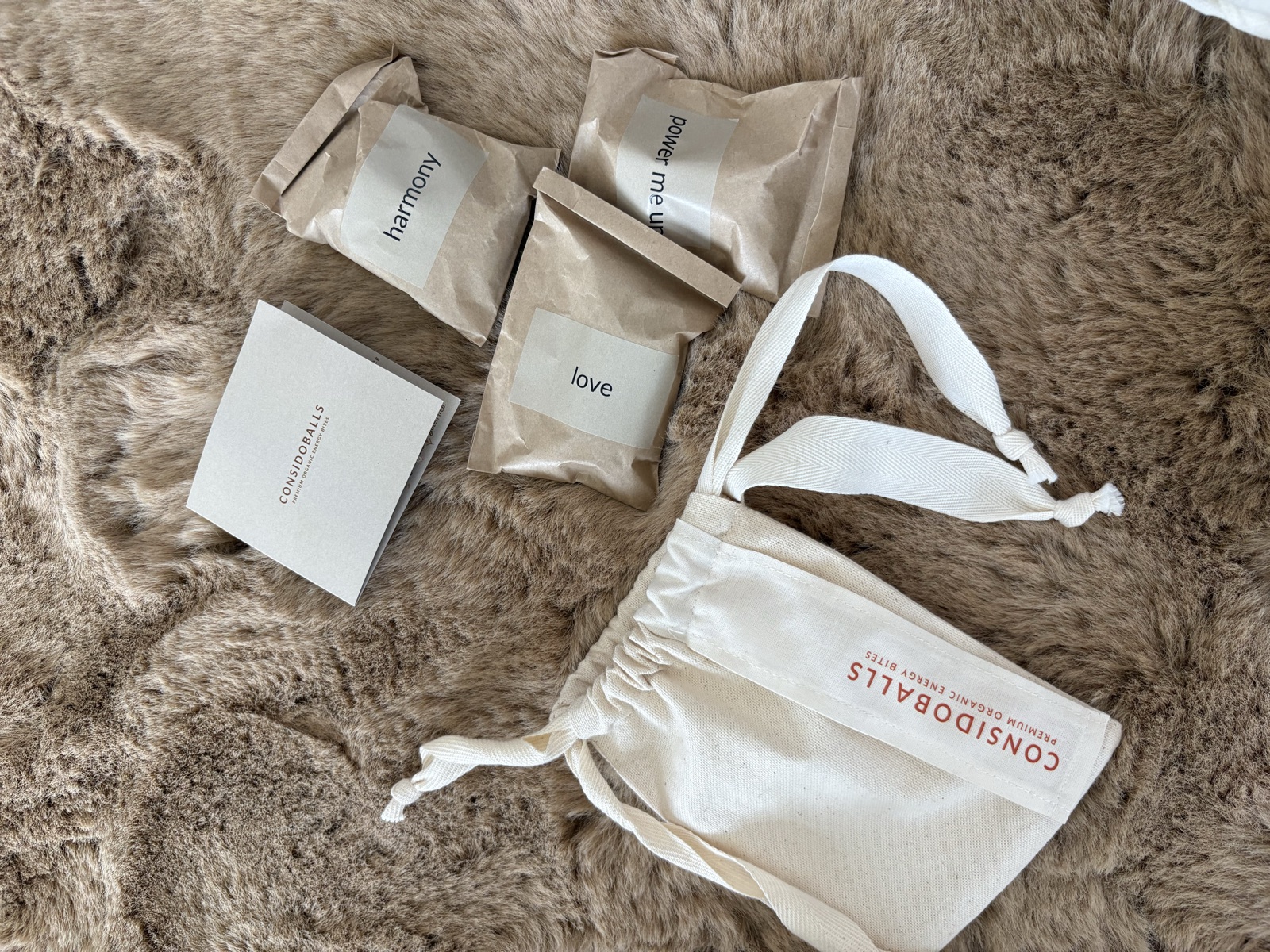 ConsidoBalls packaging on a fur rug: cotton bag, booklet and packs labelled love, harmony and power me up