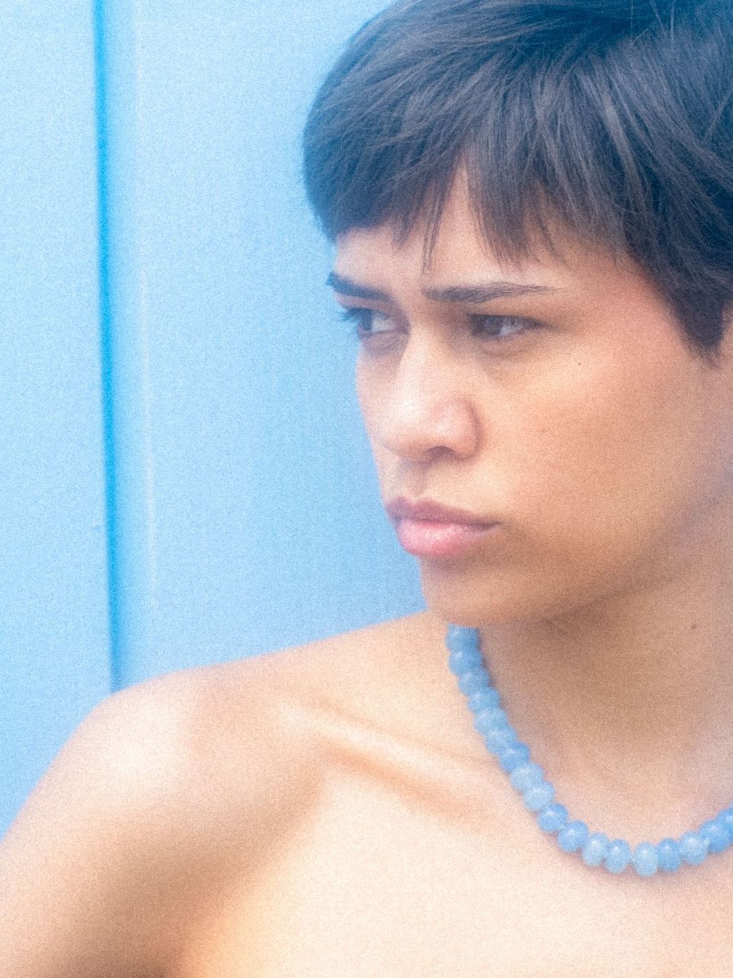 Sicels: looking aside against the blue wall, blue bead necklace