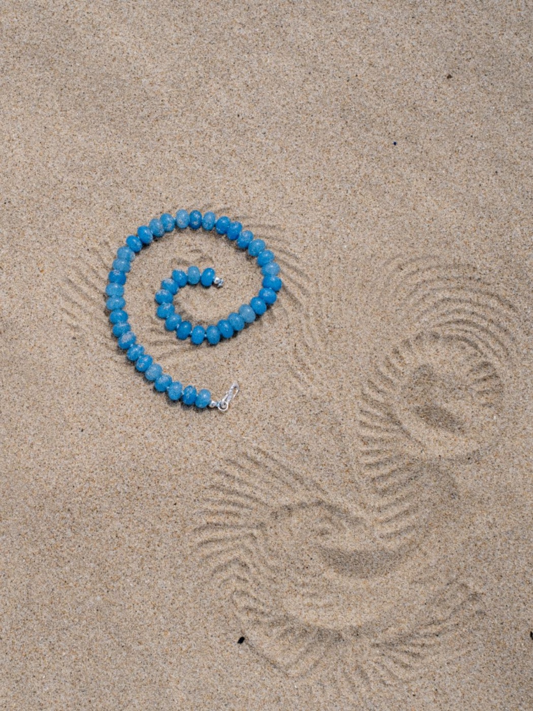 Sicels: the necklace in a spiral on sand with drawn lines